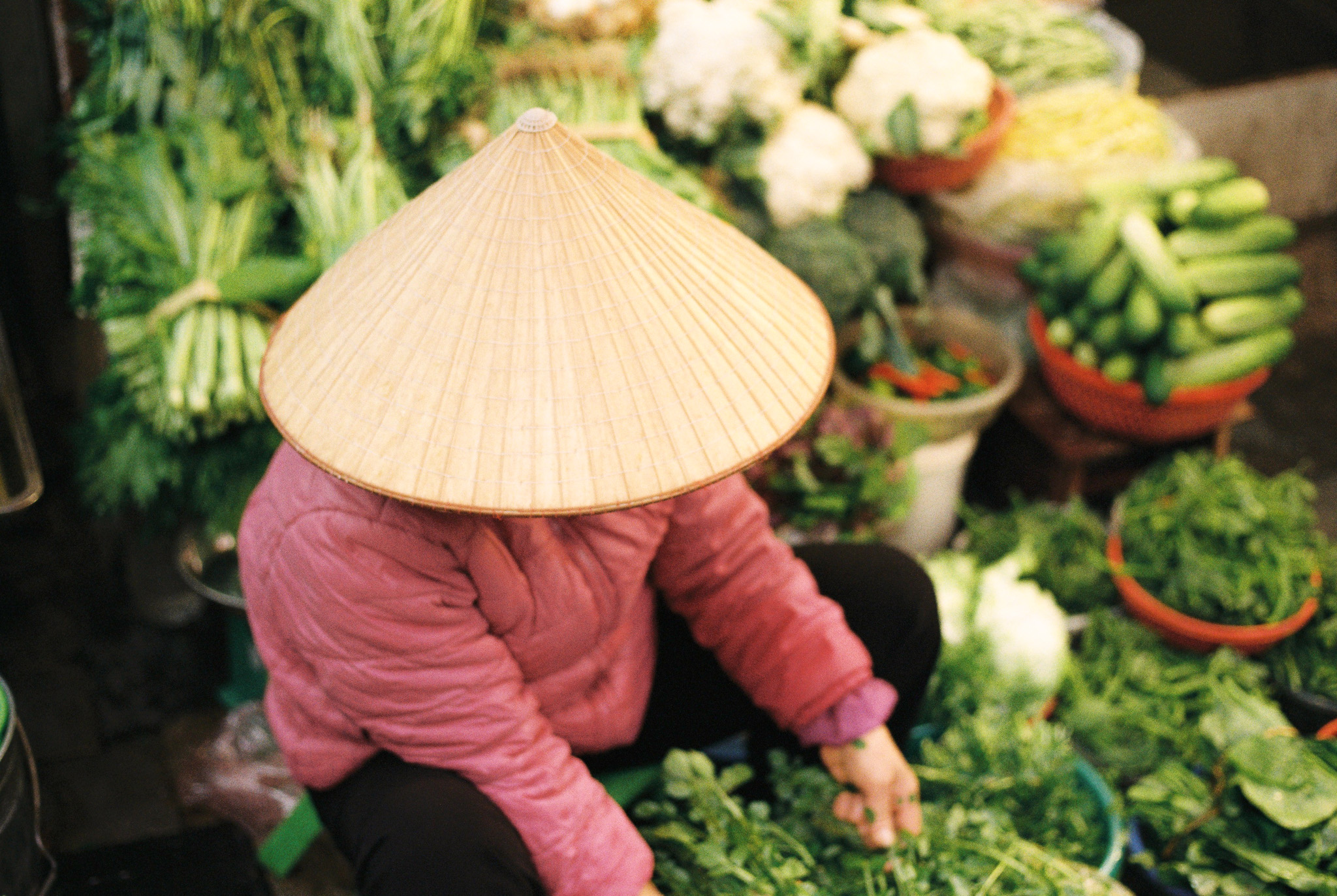 A vendor sorting fresh vegetables at a Vietnamese market